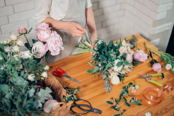 florist hands against desktop with working tools and ribbons on wood background