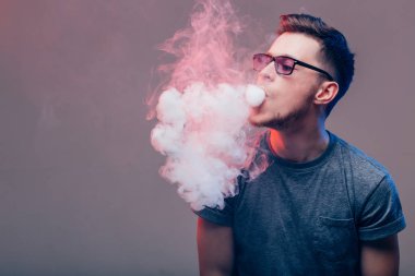 Vaper duvarın yanında elektronik sigara içiyor.