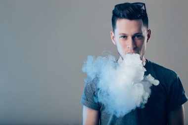Vaper duvarın yanında elektronik sigara içiyor.
