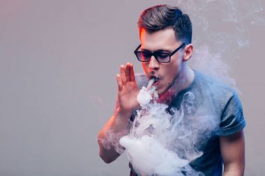 Vaper duvarın yanında elektronik sigara içiyor.