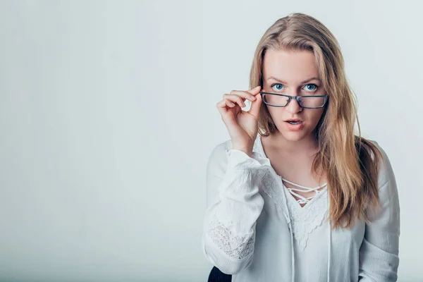 Mujer joven sorprendida en gafas sobre fondo gris — Foto de Stock