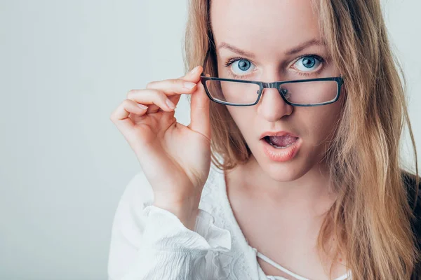Překvapený mladá žena v brýlích šedé pozadí — Stock fotografie