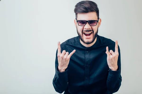 Hombre con gafas mostrando cuernos gesto de mano ambas manos y gritos felices —  Fotos de Stock