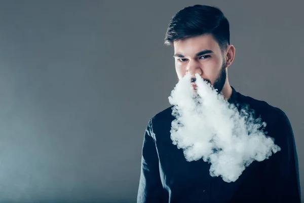 Hombres con barba en gafas de sol vapeando y liberando una nube de vapor . — Foto de Stock