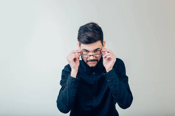 Hombre con anteojos, mirando a la cámara contra fondo gris de la pared — Foto de Stock