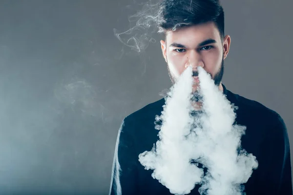 Hombres con barba en gafas de sol vapeando y liberando una nube de vapor en la nariz — Foto de Stock