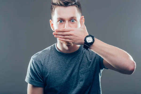 Hombre sorprendido cubriendo la boca con la mano y mirando hacia otro lado —  Fotos de Stock