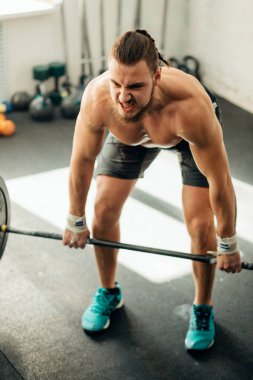 adam ağırlık kaldırıyordu. kaslı adam egzersiz halter ile egzersizleri yapıyor spor salonunda