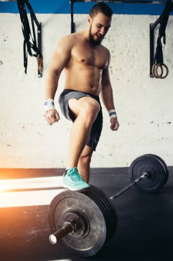 genç adam halter eğitim salonunda için hazırlanıyor. bacağını halter koymak