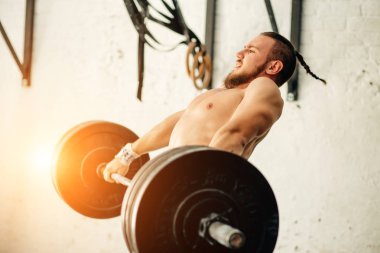 adam ağırlık kaldırıyordu. kaslı adam egzersiz halter ile egzersizleri yapıyor spor salonunda