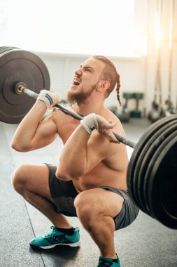 adam ağırlık kaldırıyordu. kaslı adam egzersiz halter ile egzersizleri yapıyor spor salonunda