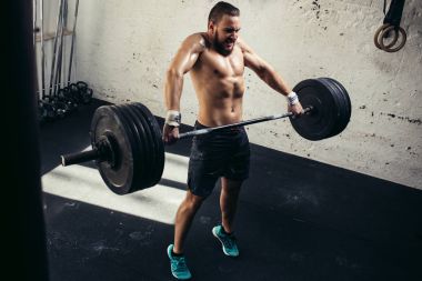 adam ağırlık kaldırıyordu. kaslı adam egzersiz halter ile egzersizleri yapıyor spor salonunda