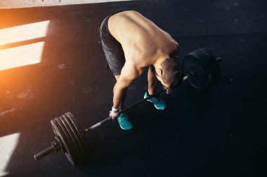 adam ağırlık kaldırıyordu. kaslı adam egzersiz halter ile egzersizleri yapıyor spor salonunda