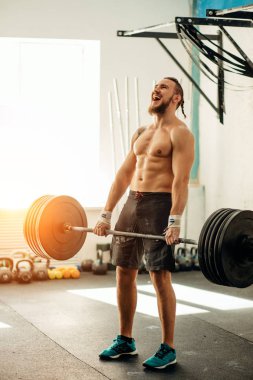 adam ağırlık kaldırıyordu. kaslı adam egzersiz halter ile egzersizleri yapıyor spor salonunda