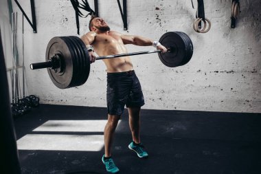 adam ağırlık kaldırıyordu. kaslı adam egzersiz halter ile egzersizleri yapıyor spor salonunda