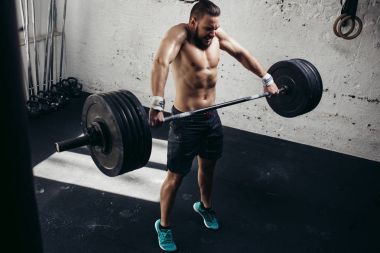 adam ağırlık kaldırıyordu. kaslı adam egzersiz halter ile egzersizleri yapıyor spor salonunda