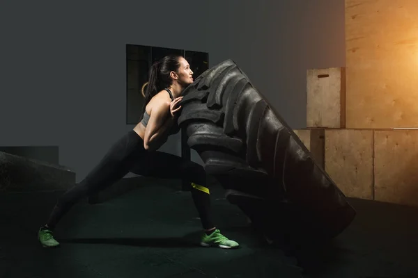 Chica fuerte volteando un neumático en el gimnasio . —  Fotos de Stock