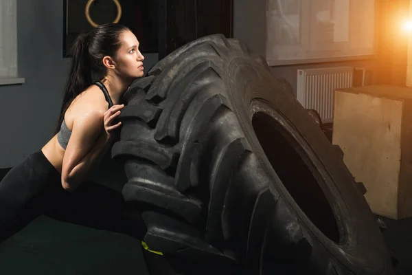 Stark tjej vända ett däck i gymmet. — Stockfoto