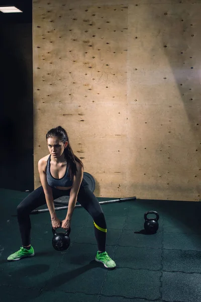 Jovem fitness mulher levantando pesado peso chaleira sino no ginásio — Fotografia de Stock