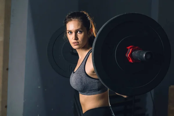 Barbell ile ağır ağırlık egzersizleri yapıyor bir spor salonunda kaslı kadın — Stok fotoğraf