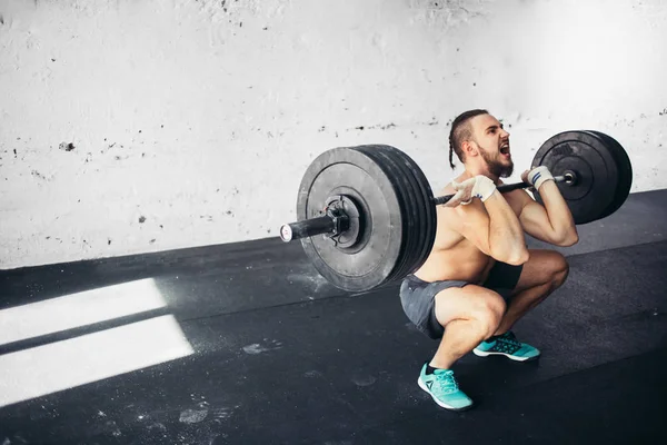 Man lyfta vikter. muskulös man träning i gym gör övningar med skivstång — Stockfoto