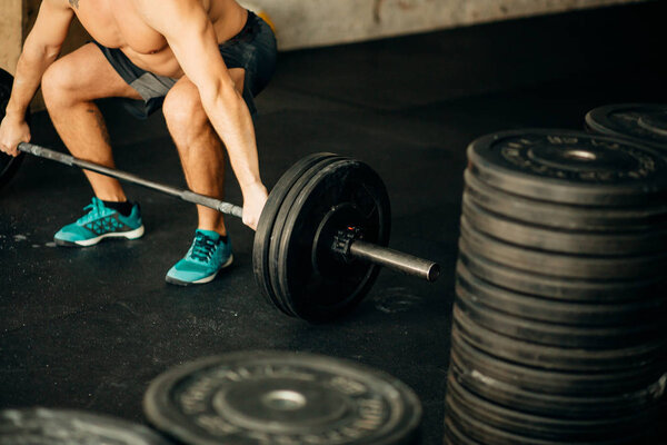 Handsome weightlifter preparing for training with barbell