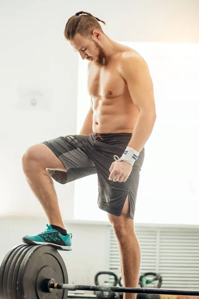 A fiatalember a felkészülés súlyemelő edzőteremben. tegye a lábát a súlyzó — Stock Fotó