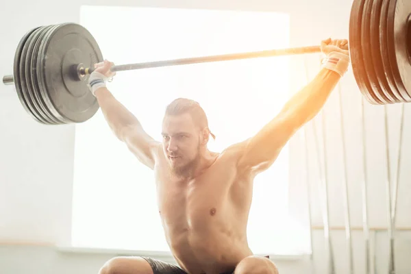 Brutal muscular man with beard train with barbell raised over head in gym — Stock Photo, Image