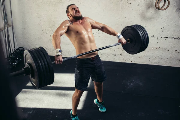 Adam ağırlık kaldırıyordu. kaslı adam egzersiz halter ile egzersizleri yapıyor spor salonunda — Stok fotoğraf