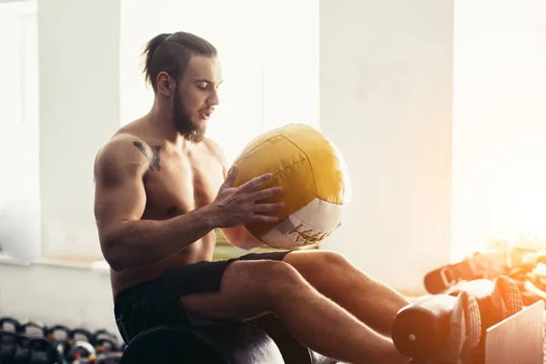 Mann macht Sit-ups mit Medizinball auf Bank, arbeitet an Bauchmuskeln — Stockfoto