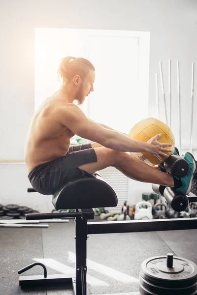 Mann macht Sit-ups mit Medizinball auf Bank, arbeitet an Bauchmuskeln — Stockfoto