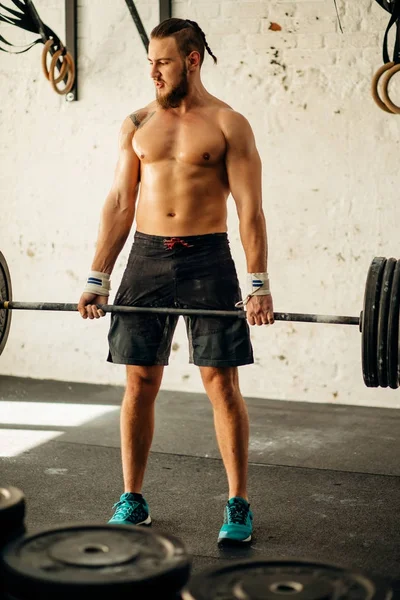 Man lyfta vikter. muskulös man träning i gym gör övningar med skivstång — Stockfoto