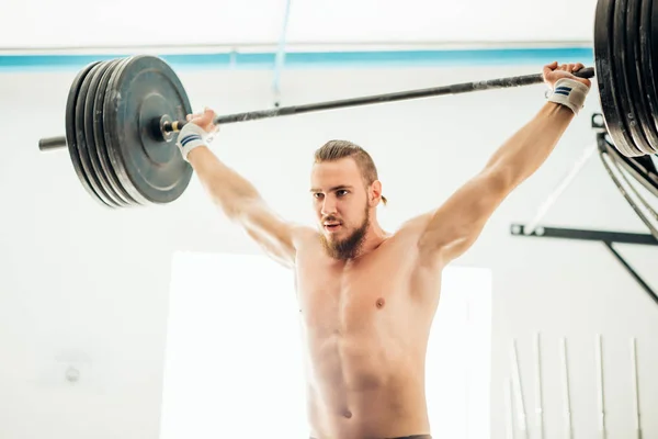 Brutal muscular homem com barba trem com barbell levantado sobre cabeça no ginásio — Fotografia de Stock