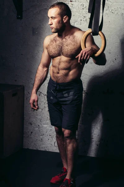 Genç kaslı çekici adam çıplak gövde jimnastik halkalar karşı poz