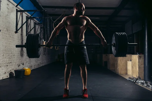 Muskulöser Mann trainiert im Fitnessstudio Übungen mit der Langhantel — Stockfoto