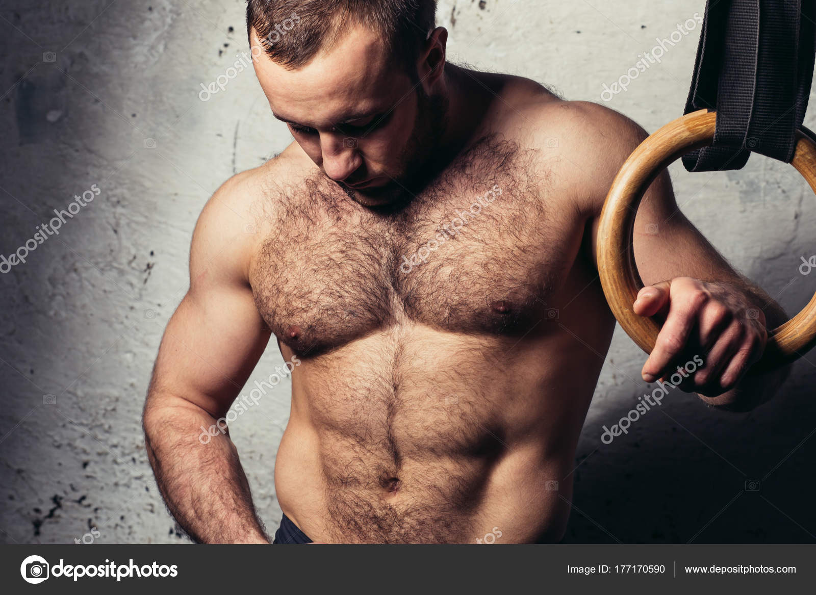 Young muscular attractive man naked torso posing against gymnastics