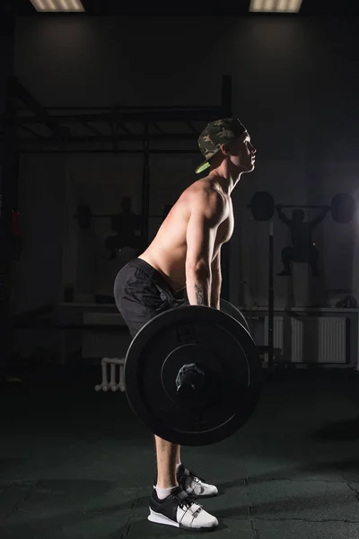 Hombre levantando pesas. entrenamiento de hombre muscular en el gimnasio haciendo ejercicios con barra — Foto de Stock