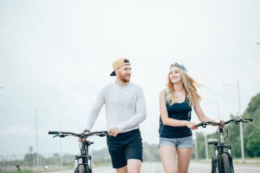 Genç çift Bisiklet birlikte yolda yürürken