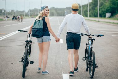 Bisiklet birlikte mercek parlaması ile çarpıcı günbatımı için yolda yürürken Çift