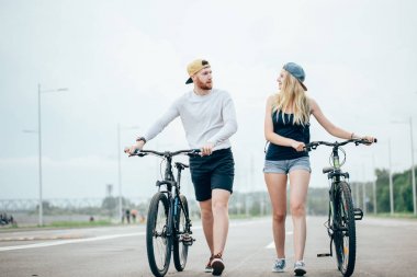 Bisiklet birlikte mercek parlaması ile çarpıcı günbatımı için yolda yürürken Çift