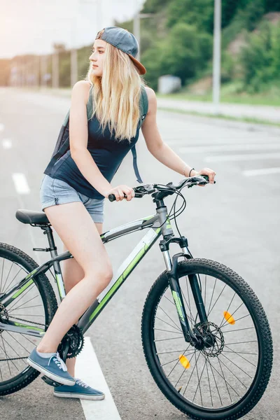 Fille sur un vélo printemps matin sur la route — Photo