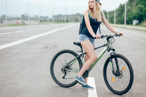 Vista lateral retrato de uma jovem bela mulher andando de bicicleta na rua da cidade — Fotografia de Stock