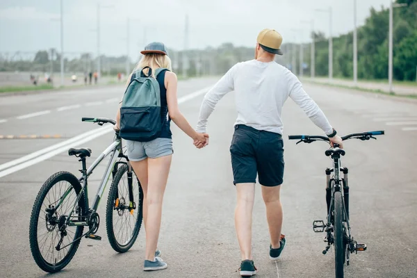 Homme et femme marchent leurs vélos sur la route — Photo