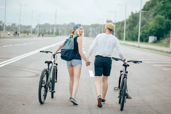 Couple de vélos de marche ensemble sur la route au coucher du soleil magnifique avec lentille fusée éclairante — Photo