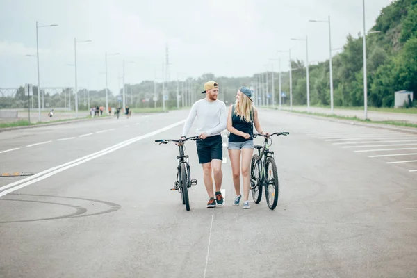 Homme et femme marchent leurs vélos sur la route — Photo