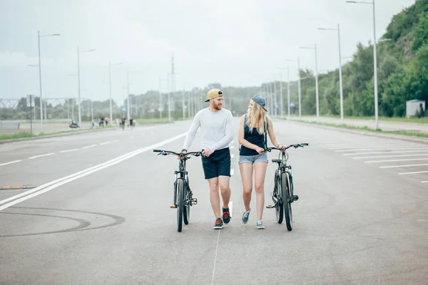렌즈 플레어 멋진 일몰도 함께 자전거를 산책 하는 커플 — 스톡 사진