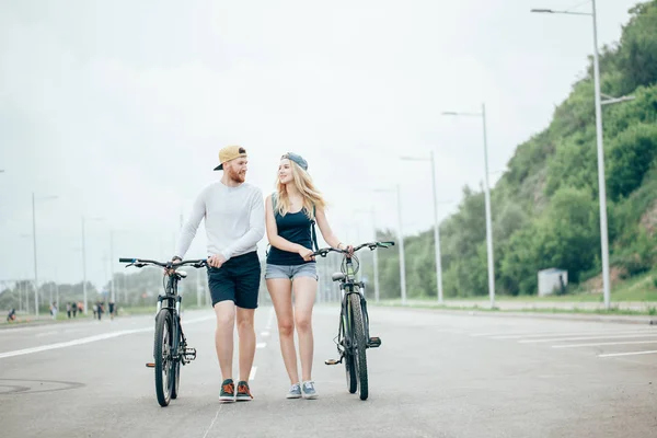 快乐年轻夫妇手牵着手和骑自行车 — 图库照片