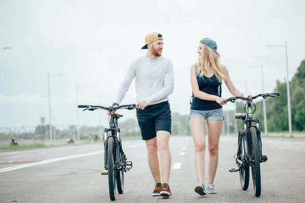 Coppia di biciclette a piedi insieme sulla strada per il tramonto mozzafiato con bagliore lente — Foto Stock