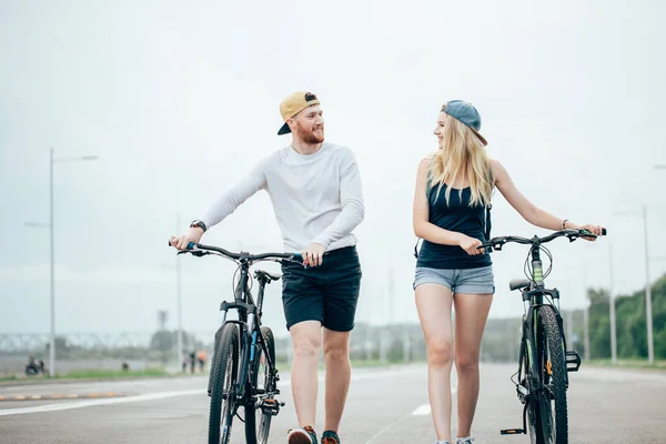 Glückliches junges Paar hält Händchen und radelt — Stockfoto