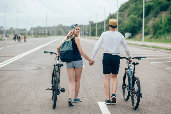 Homme et femme marchent leurs vélos sur la route — Photo